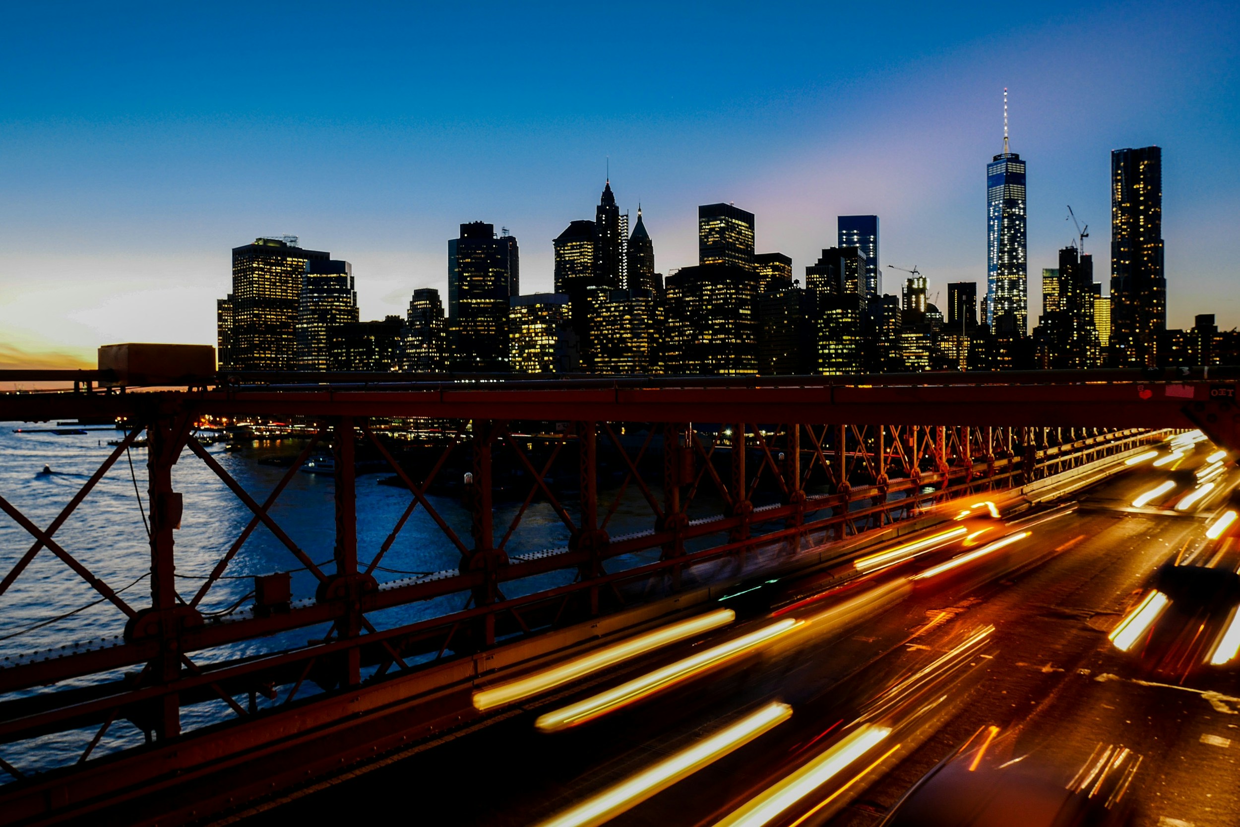 A long-exposure shot of light trails on the freeway with the New York city skyline at the back